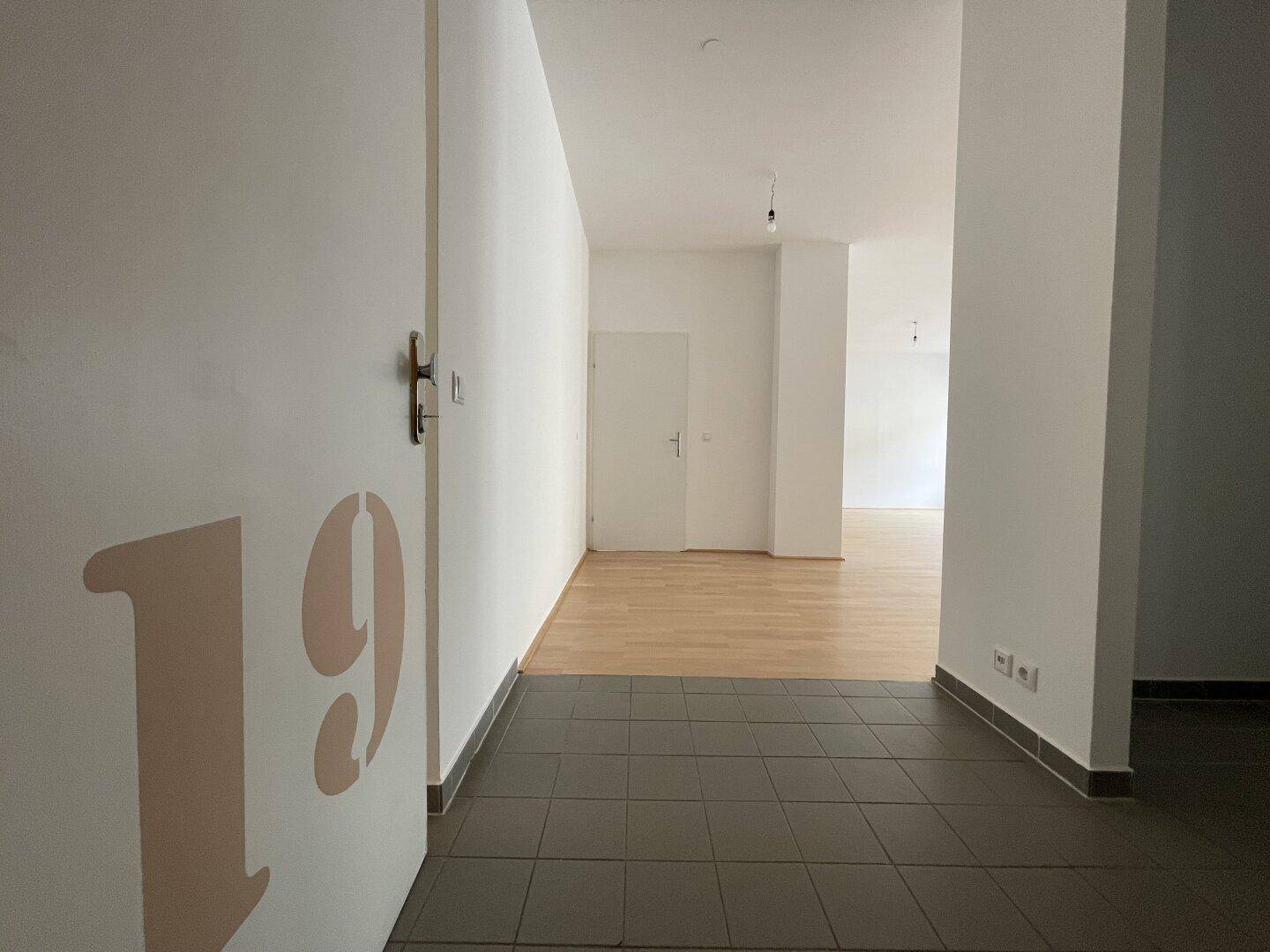 Eingangsbereich der Wohnung mit Fliesenboden und Blick in den hellen Wohnbereich.