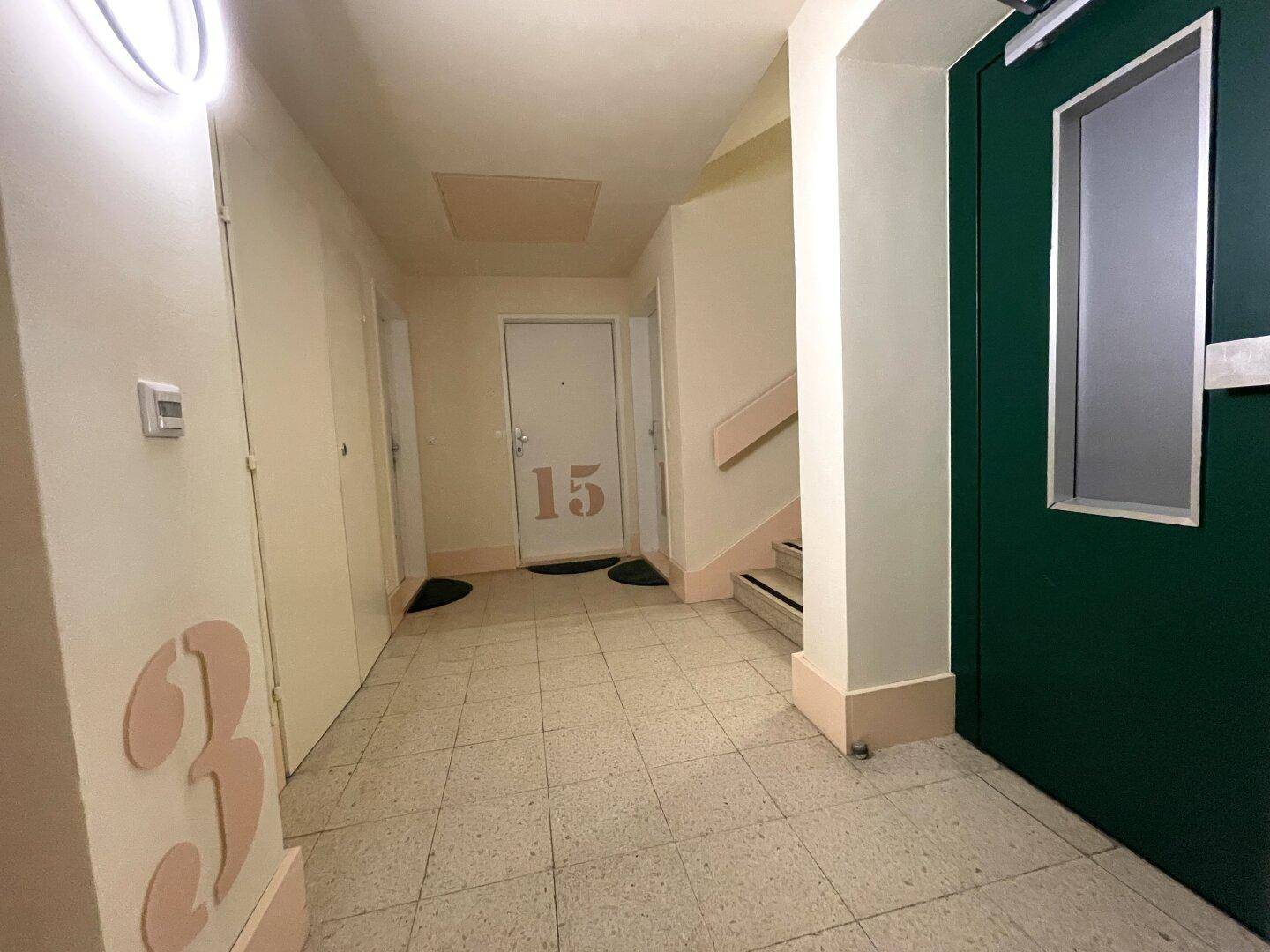 Heller Hausflur mit Fliesenboden, Aufzug und Türen zu den verschiedenen Wohneinheiten.