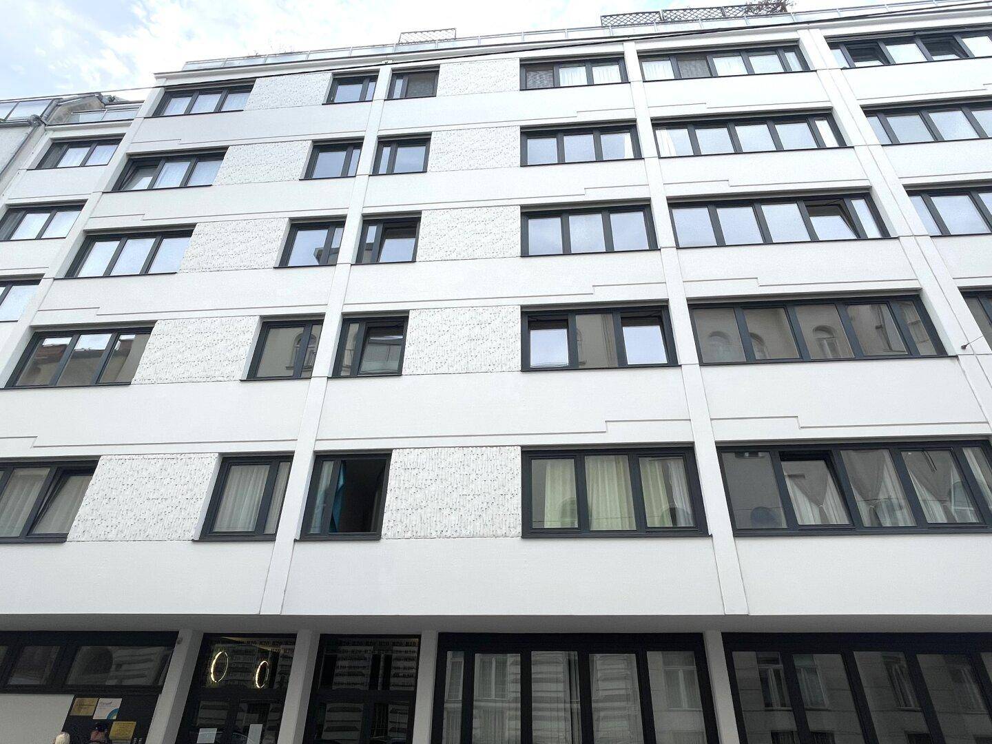 Moderne Gebäudefassade mit zahlreichen Fenstern und schlichter, weißer Gestaltung.