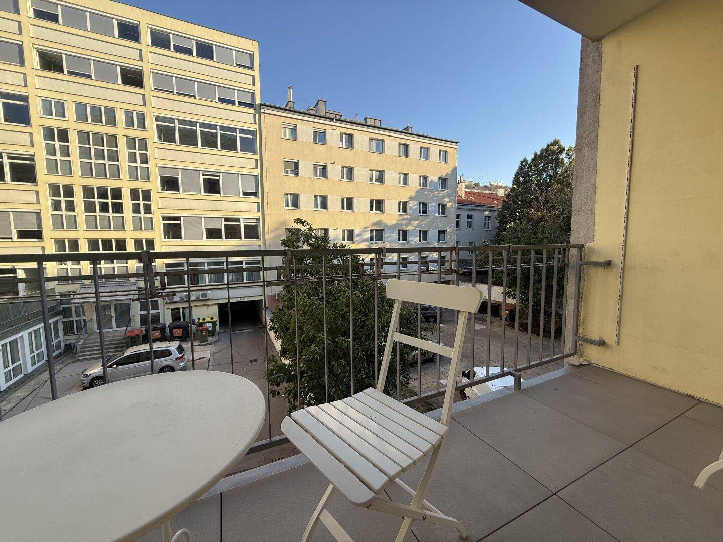 Balkon mit einfacher Bestuhlung bietet einen Ausblick auf den städtischen Innenhof.