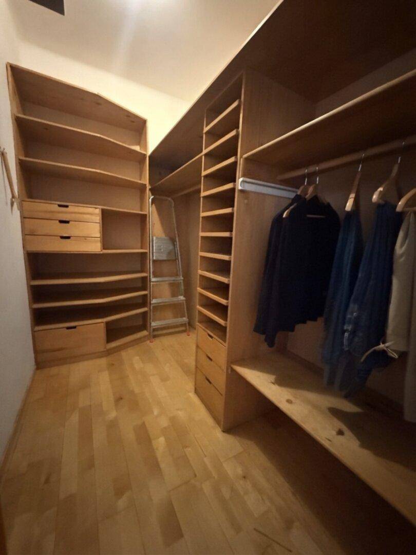 Geräumiger begehbarer Kleiderschrank mit maßgefertigten Holzregalen und Schubladen.