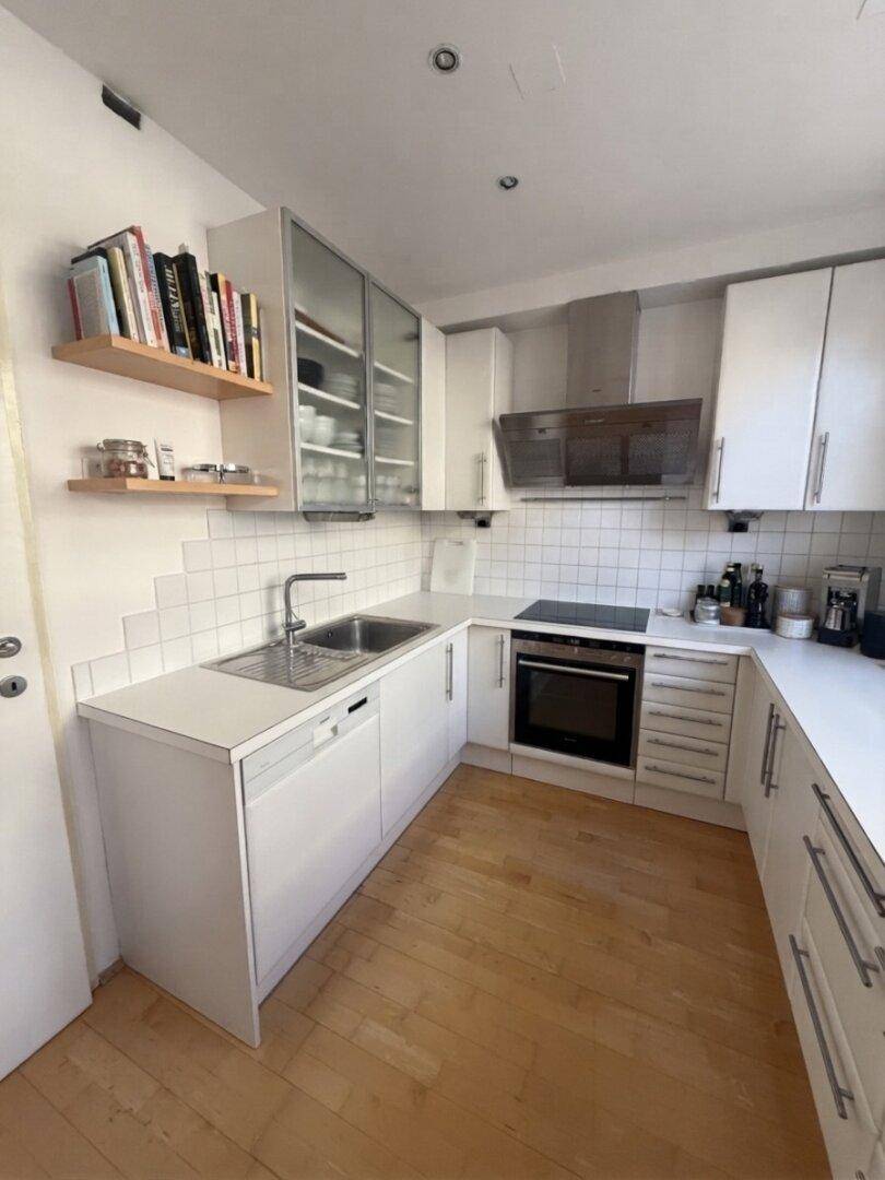Moderne U-förmige Küche mit weißen Schränken, integrierten Geräten und Holzregalen.