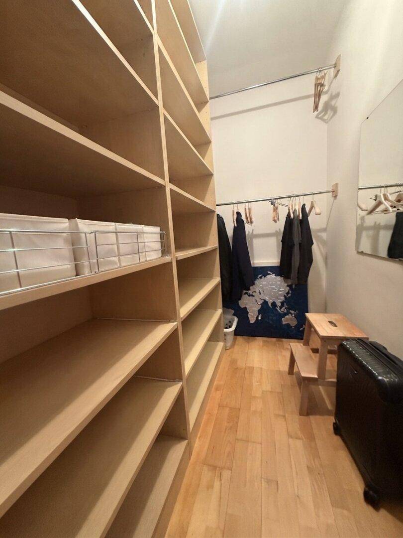 Praktischer Abstellraum mit umfangreichen Holzregalen und Kleiderstange für viel Stauraum.