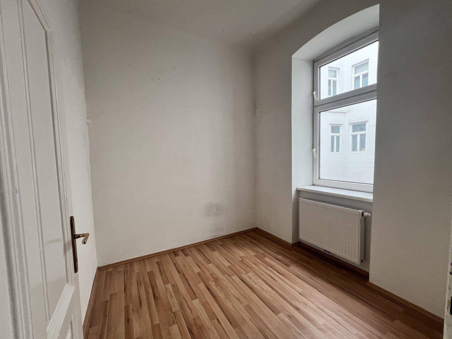 Kleines, helles Zimmer mit Laminatboden und Fenster, ideal als Schlaf- oder Arbeitszimmer.