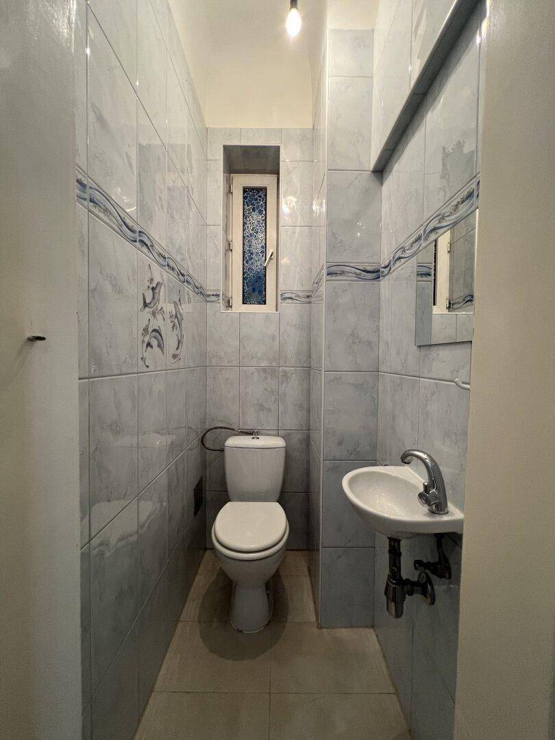 Kleines Gäste-WC mit WC, Waschbecken und Fenster, komplett gefliest.