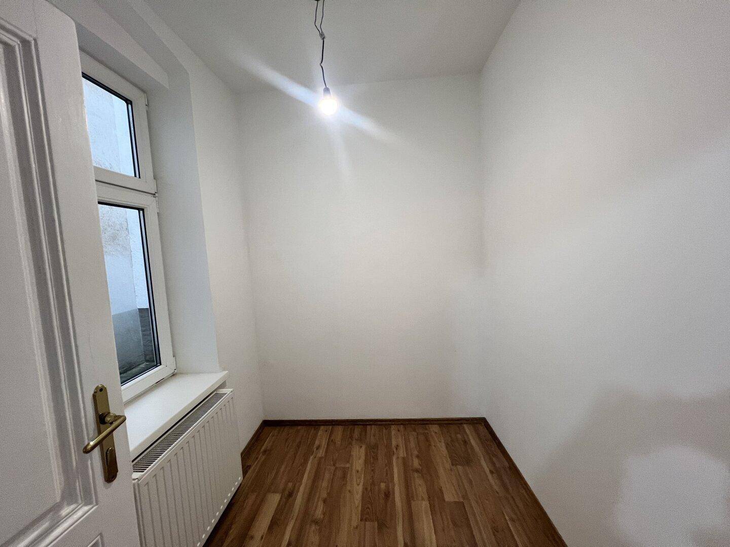 Kleiner, heller Raum mit Laminatboden und einem Fenster, ideal als Abstellraum oder Büro.