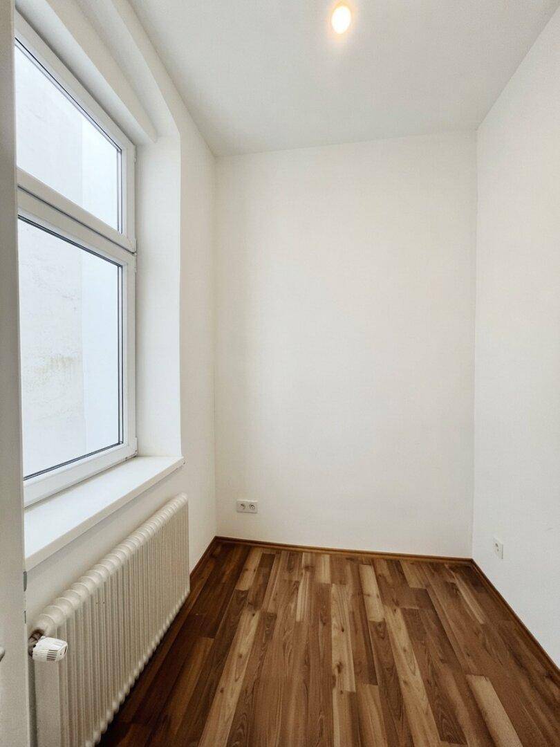 Kleines, helles Zimmer mit Parkettboden und Fenster, ideal als Kinderzimmer oder Büro.