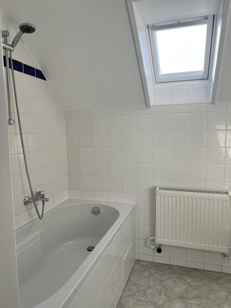 Badezimmer mit Badewanne, Dachfenster und weißen Fliesen, hell und funktional.