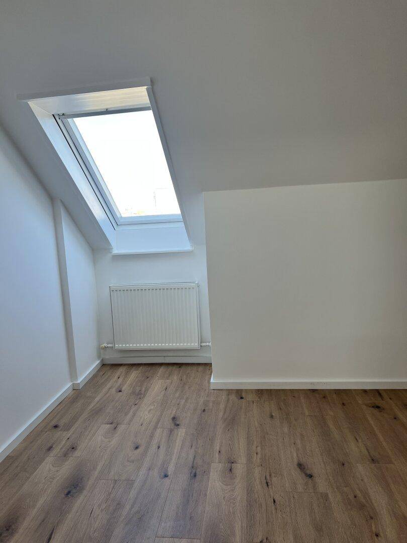 Geräumiges Schlafzimmer im Dachgeschoss mit Holzboden und viel Tageslicht durch das Dachfenster.