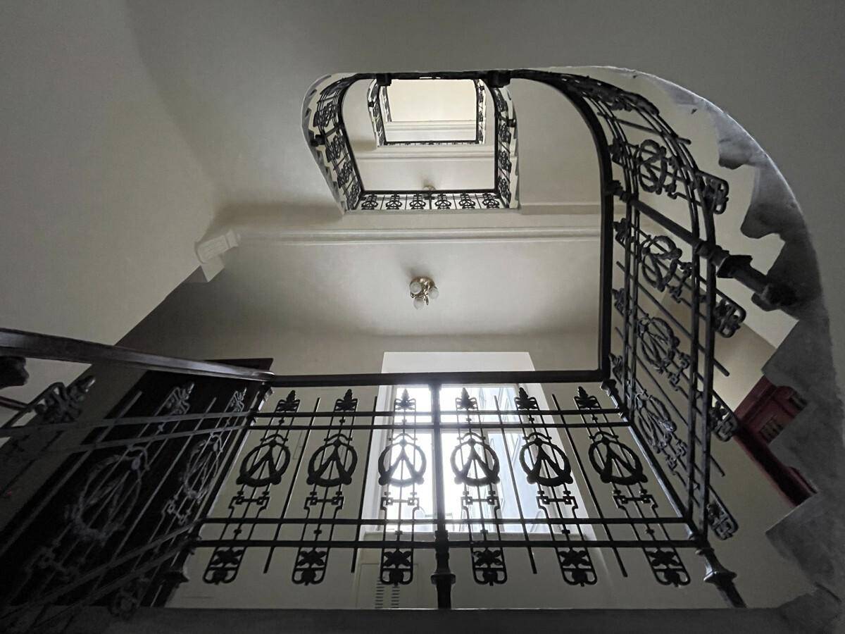 Historisches Treppenhaus mit kunstvollem schmiedeeisernem Geländer und natürlichem Lichteinfall von oben.