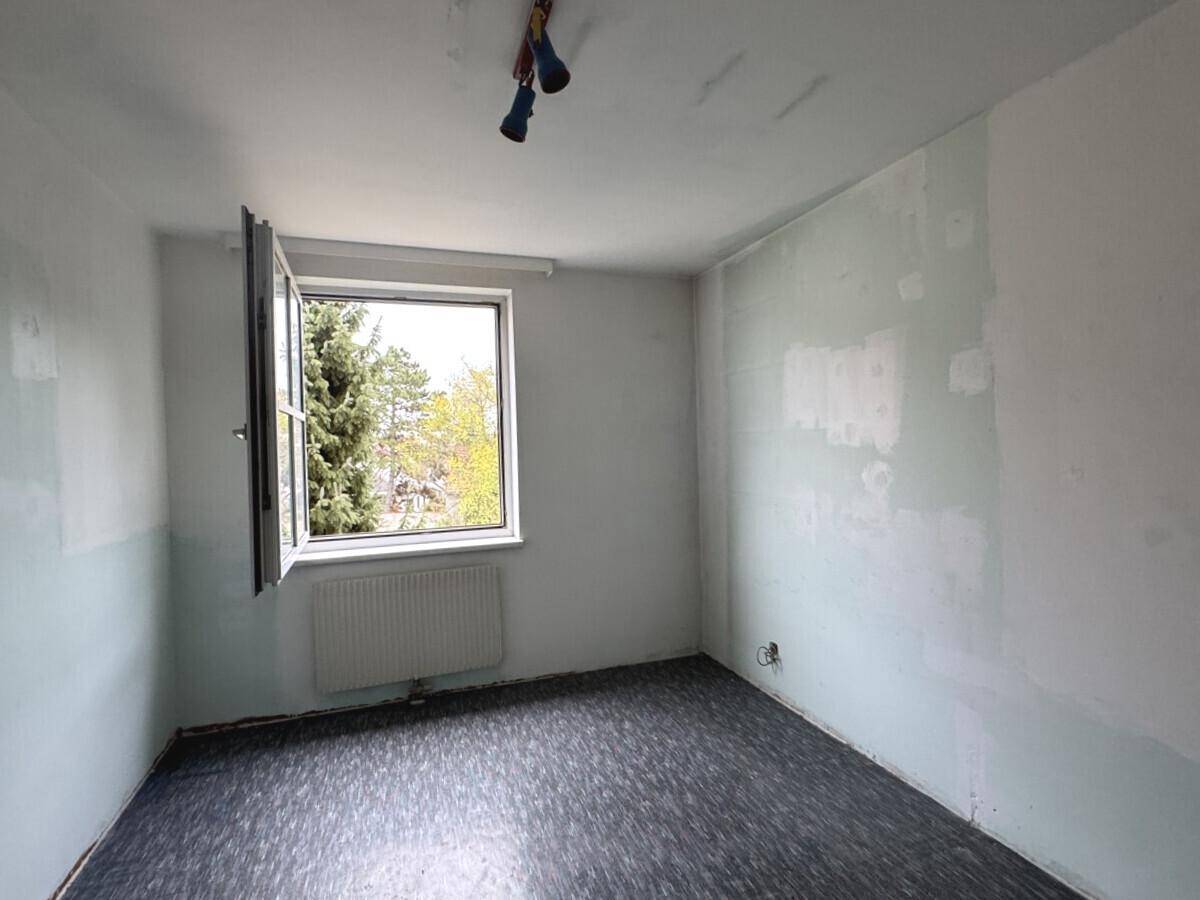 Leeres Zimmer mit Vinylboden und sichtbaren Spuren, die eine Renovierung erfordern.