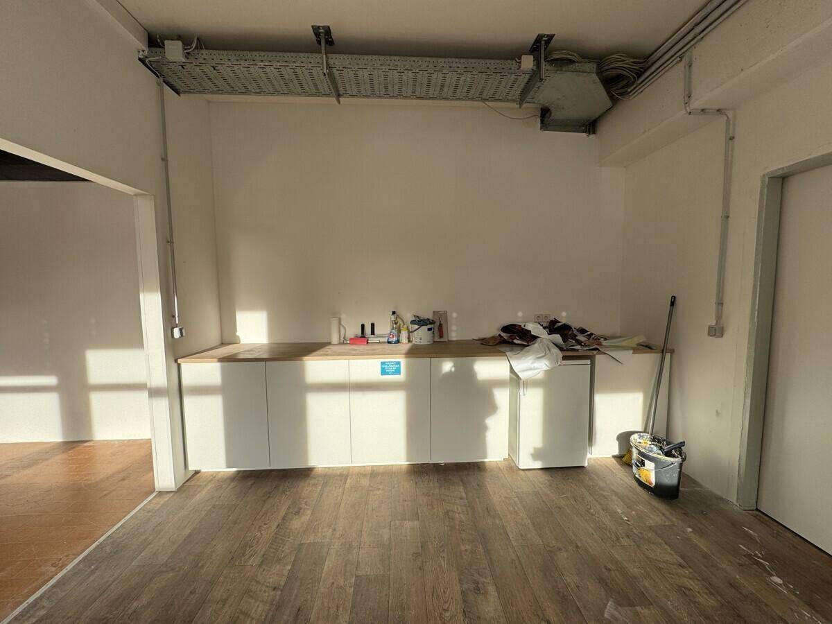 Bereich mit Arbeitsplatte, Unterschränken und sichtbaren Kabeltrassen an der Decke.