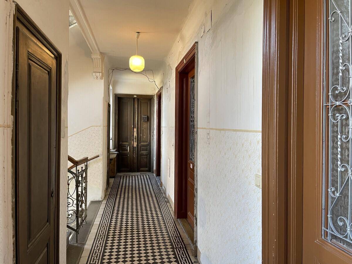 Langer Flur in einem Altbau mit charakteristischen gemusterten Bodenfliesen und Holztüren.