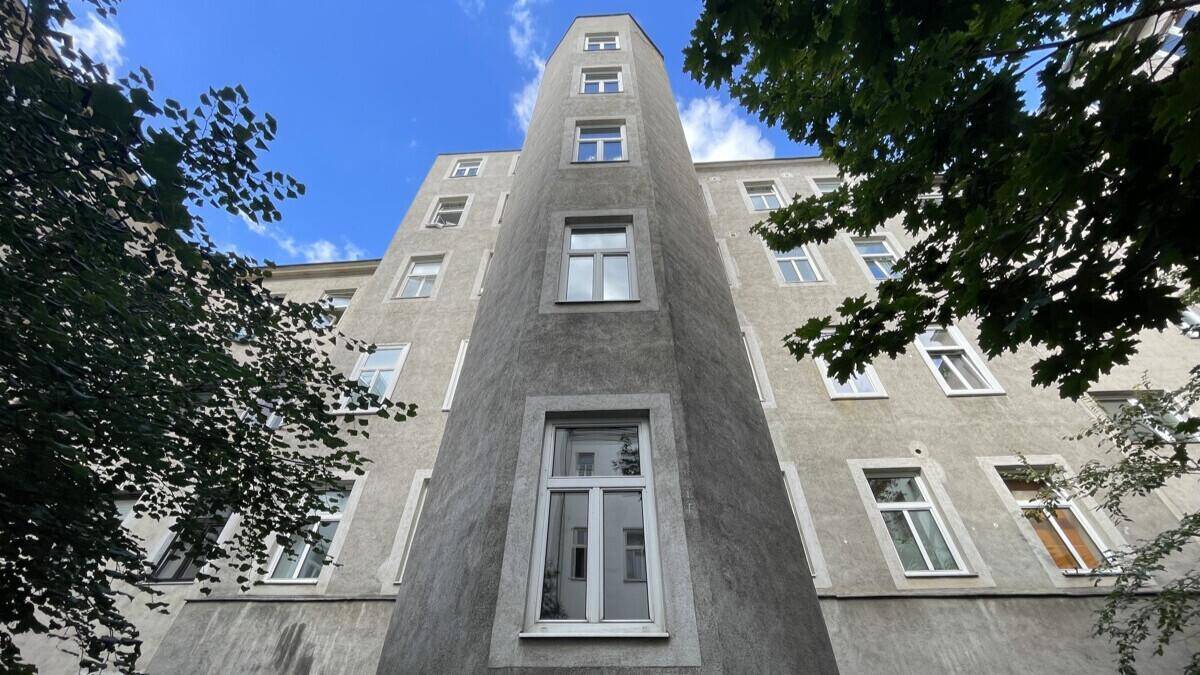 Hohe, schmale Gebäudefassade mit vielen Fenstern unter blauem Himmel.