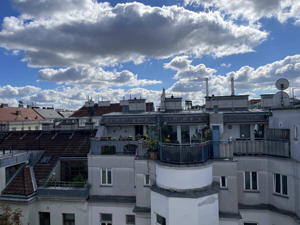 Weitläufiger Blick über Dächer mit Terrassen und dem Himmel über der Stadt.