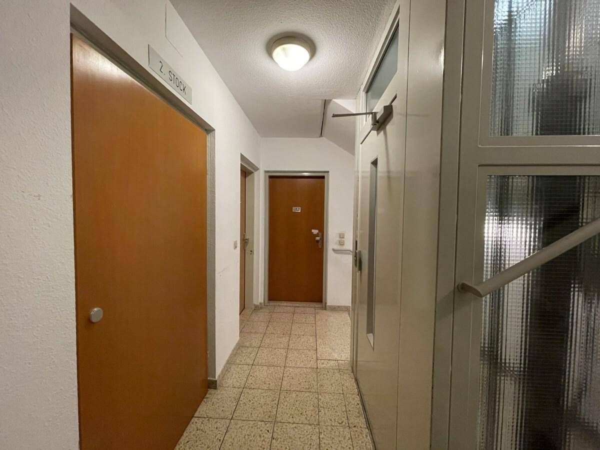 Heller Hausflur mit Fliesenboden und Holztüren, der Zugang zu den Wohnungen bietet.
