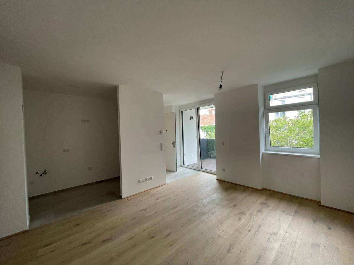 Geräumiger, heller Wohnbereich mit Holzboden und Schiebetür zum Außenbereich.