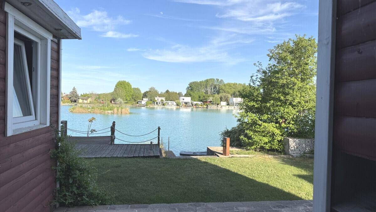 Idyllischer Blick auf den See von der Terrasse mit direktem Zugang zum Wasser und grüner Umgebung.