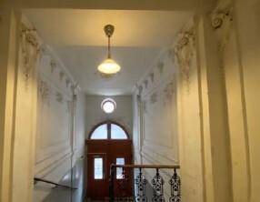 Elegantes Treppenhaus eines Altbaus mit Stuckverzierungen und hohen Decken.