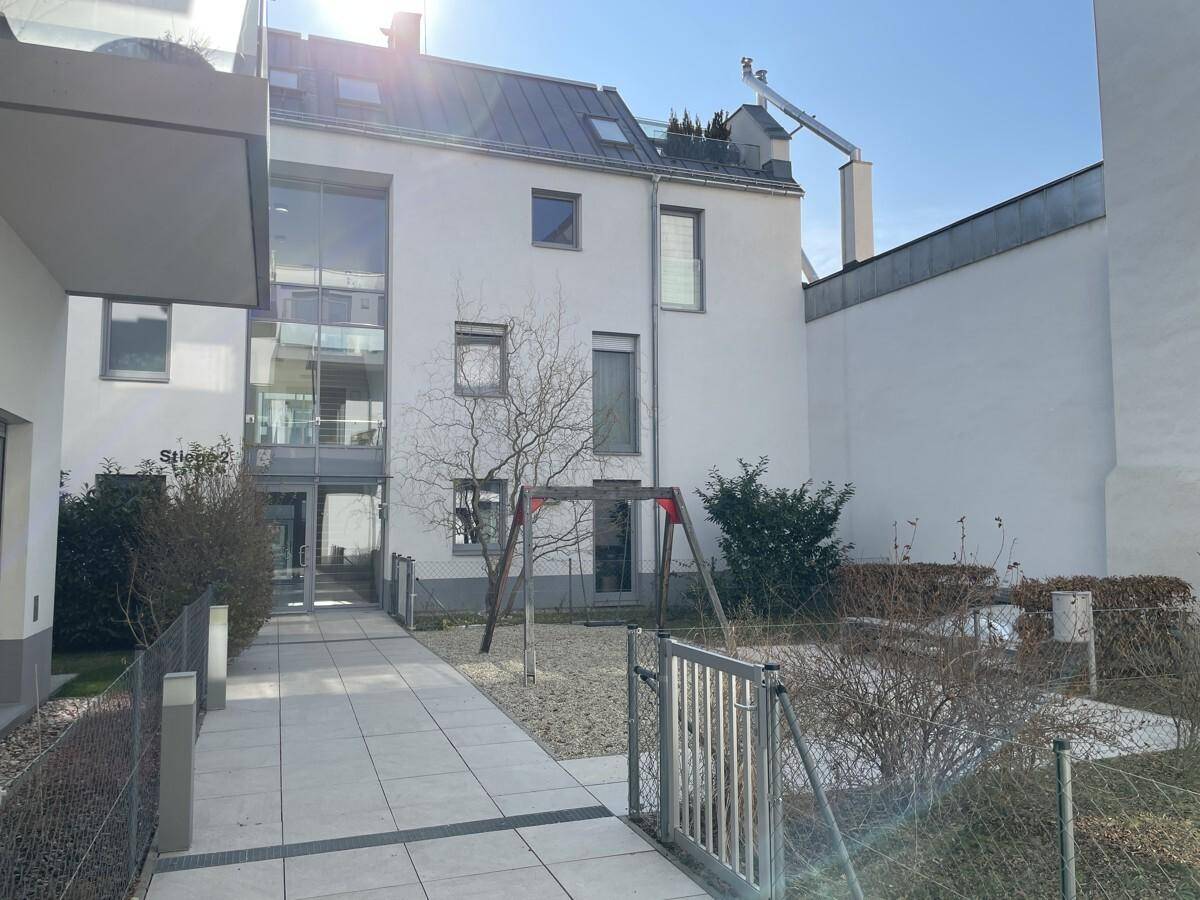 Außenansicht eines modernen Gebäudes mit Innenhof und kleinem Spielplatz.