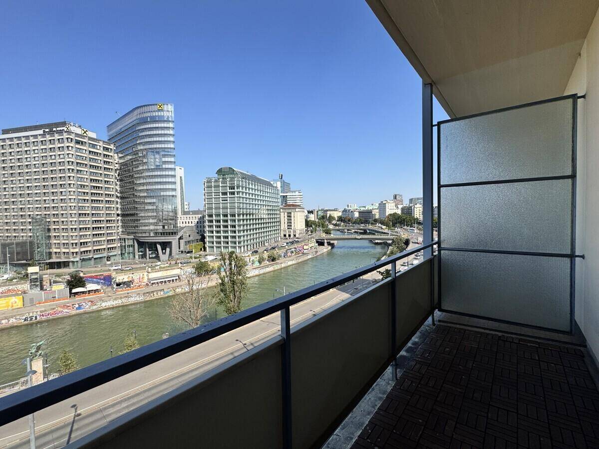 Balkon mit Holzboden und Glasabtrennung bietet einen weiten Blick auf die Stadt und den Fluss.