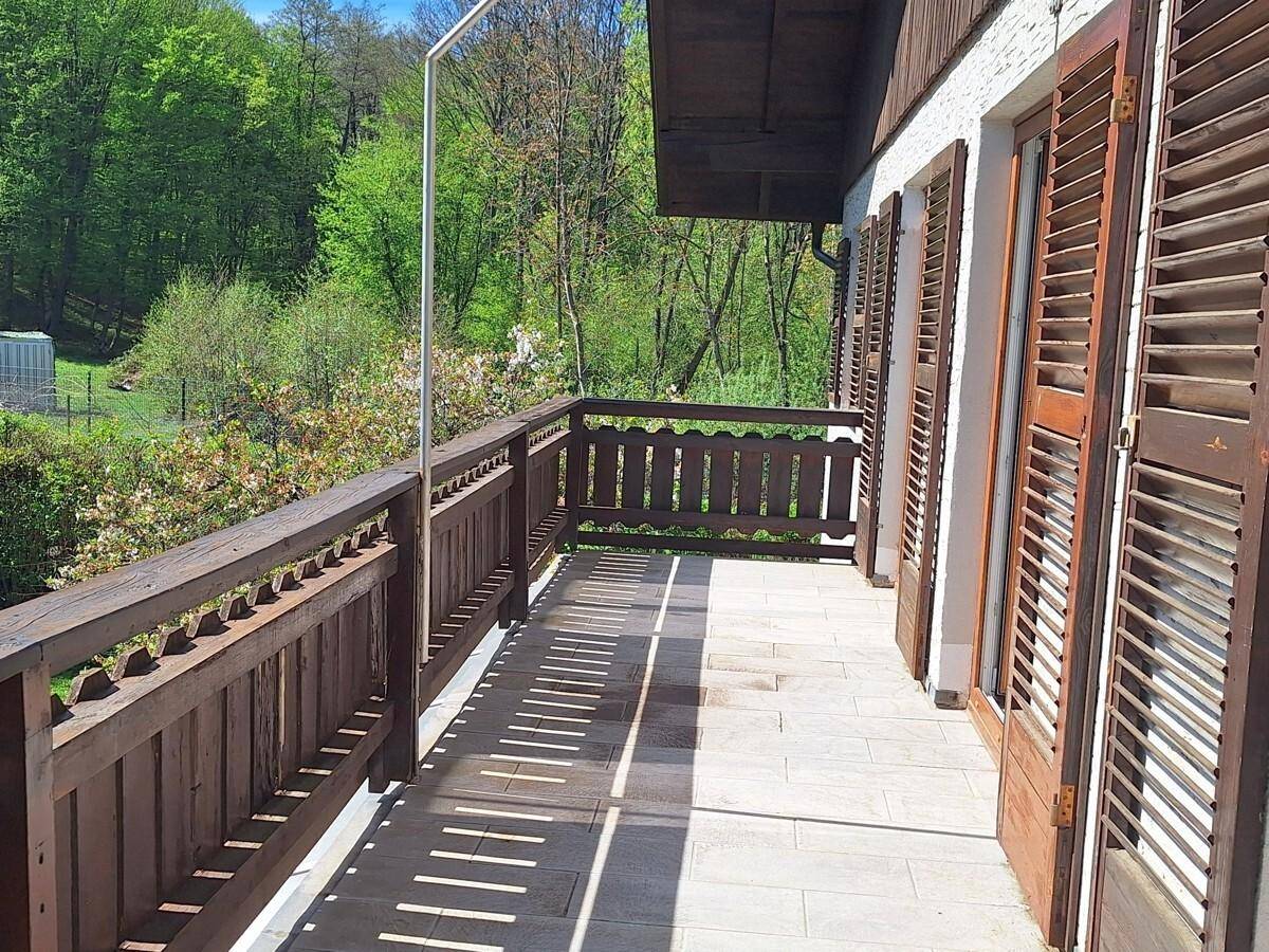Langer Balkon mit Holzgeländer und weitem Blick ins Grüne, ideal zum Entspannen an der frischen Luft.