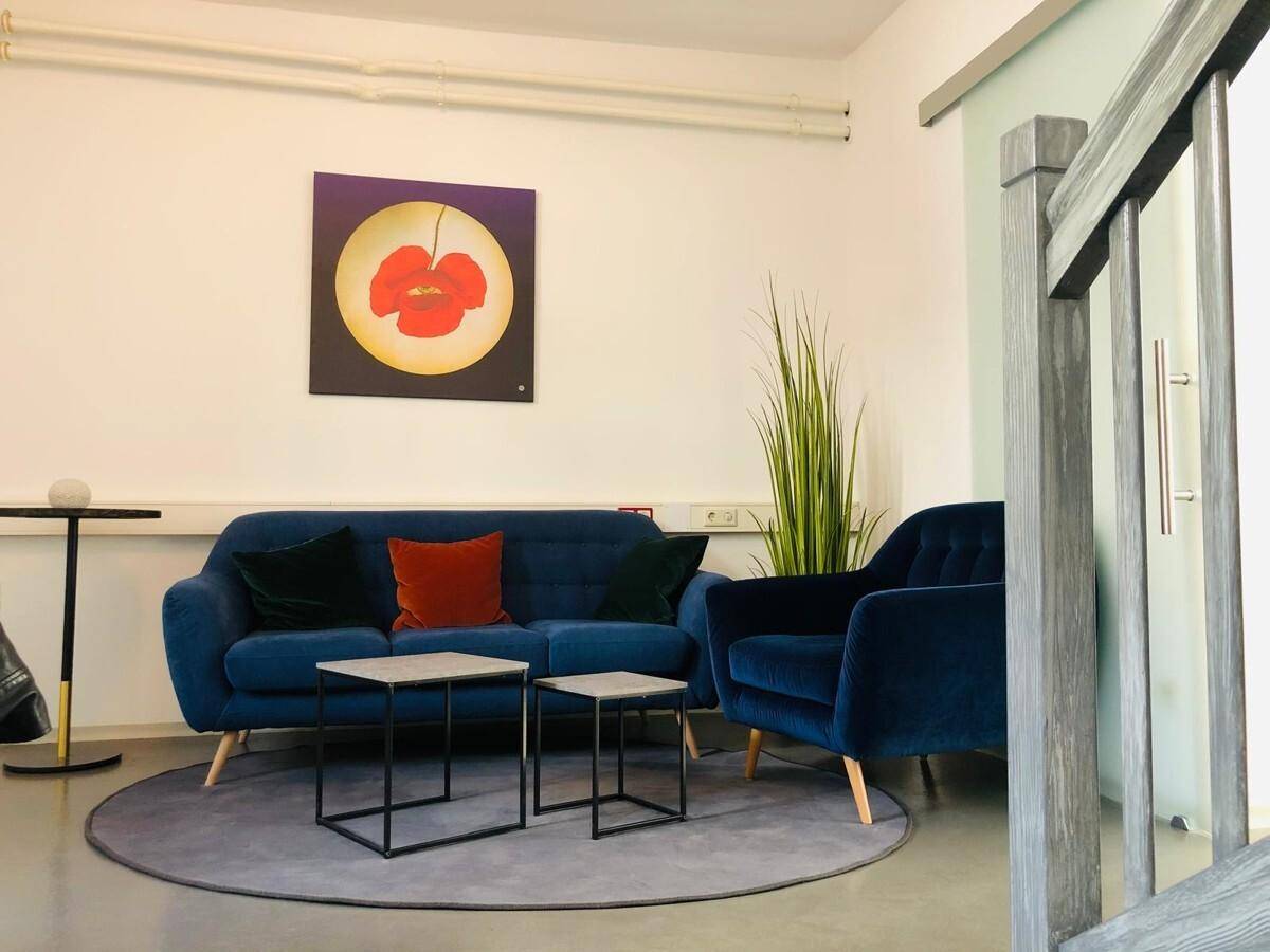 Komfortabler Lounge-Bereich mit blauen Sofas, Beistelltischen und einem runden Teppich für entspannte Momente.