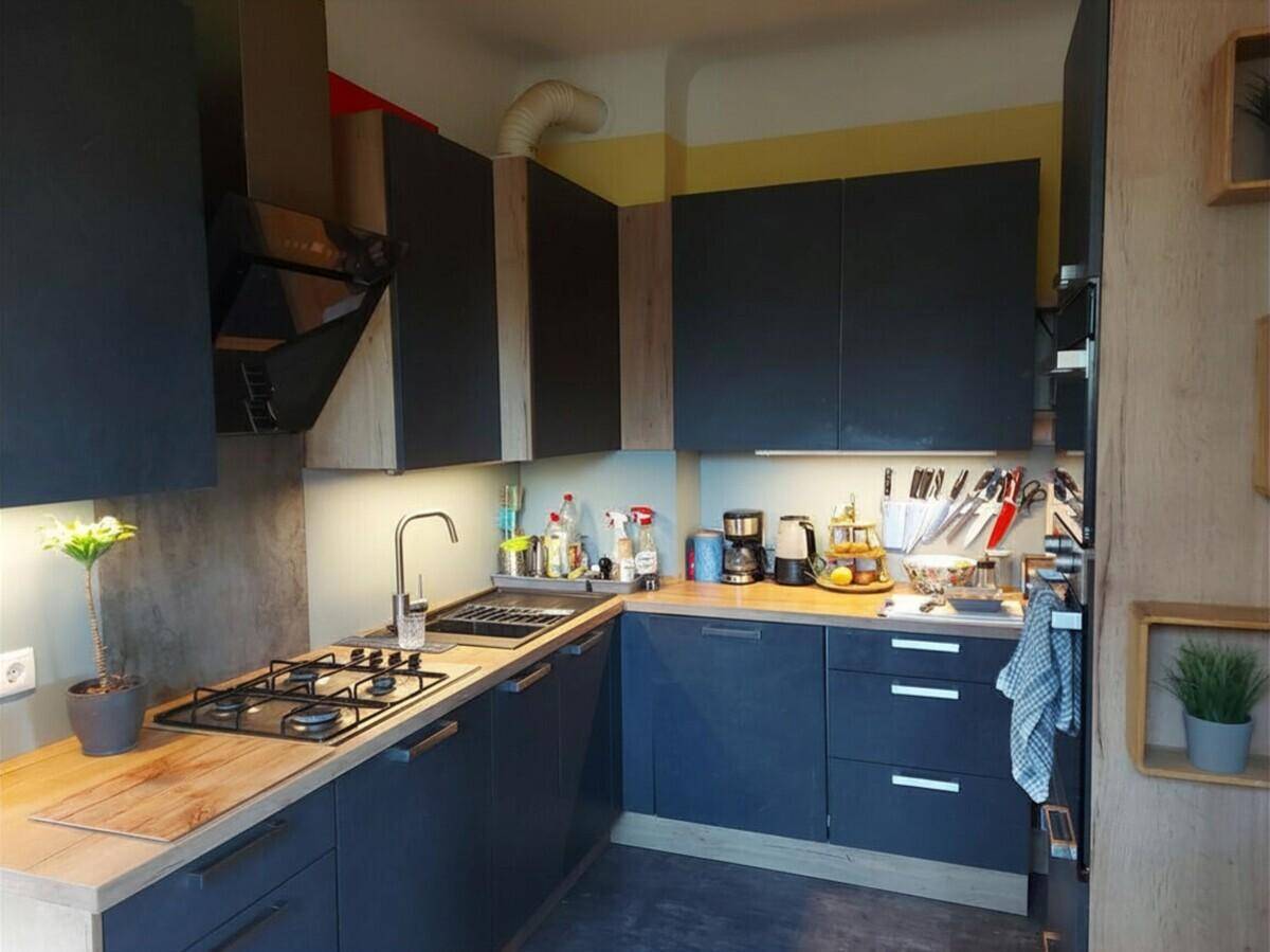 Moderne Küche mit dunklen Schränken, Holz-Arbeitsplatten und Gasherd.
