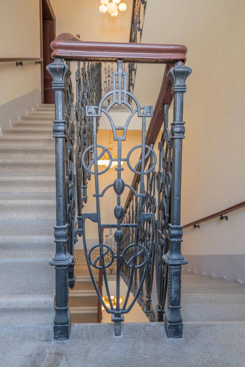 Nahaufnahme des kunstvoll geschmiedeten Geländers im historischen Treppenhaus.