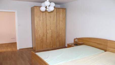 Schlafzimmer mit hellem Holzschrank, passendem Bettrahmen und Nachttisch, ausgestattet mit Holzboden.