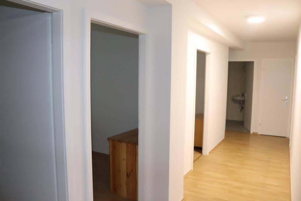 Heller Flur mit Holzboden und mehreren Türen, die zu den angrenzenden Räumen führen.