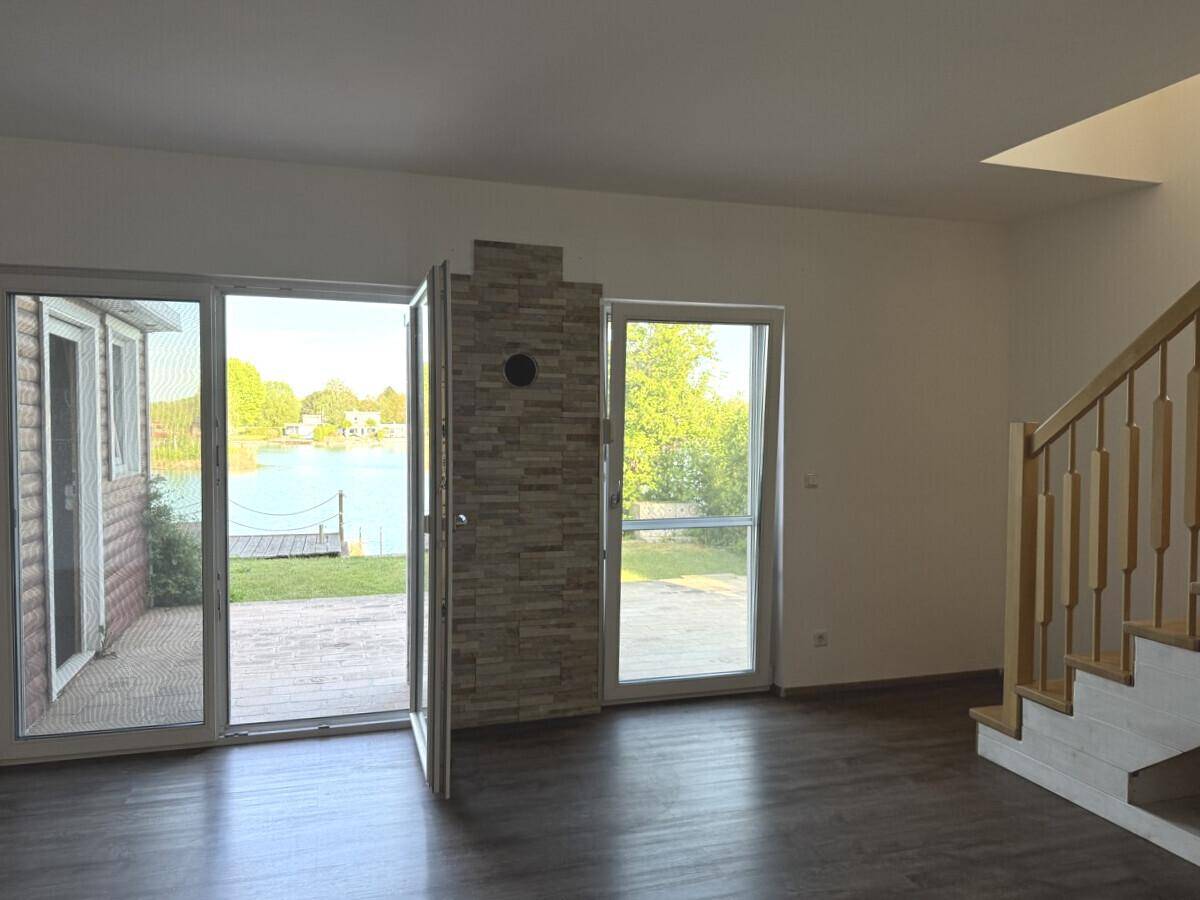 Lichtdurchfluteter Wohnraum mit direktem Zugang zum Garten und weitem Blick auf den See.