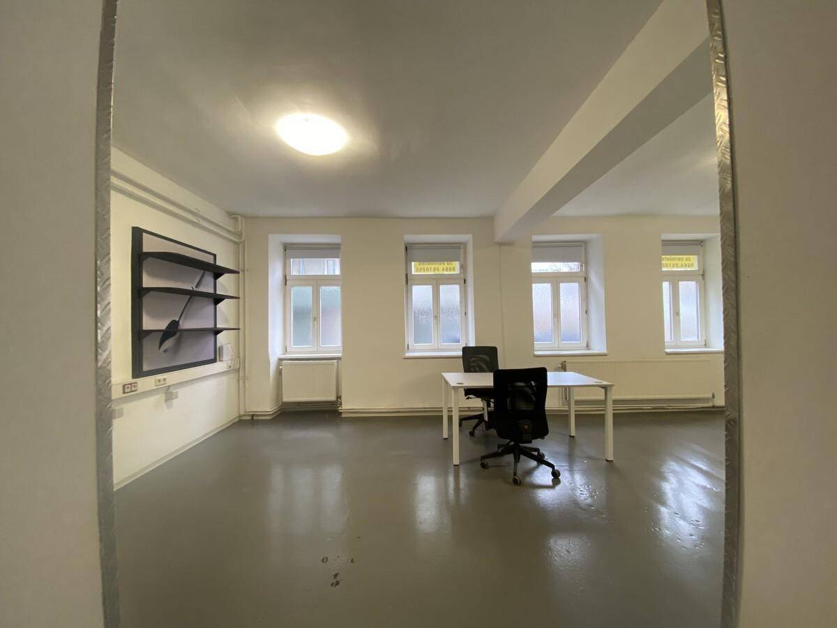 Heller Büroraum mit mehreren Fenstern, zwei Schreibtischen und Bürostühlen, bereit zur sofortigen Nutzung.