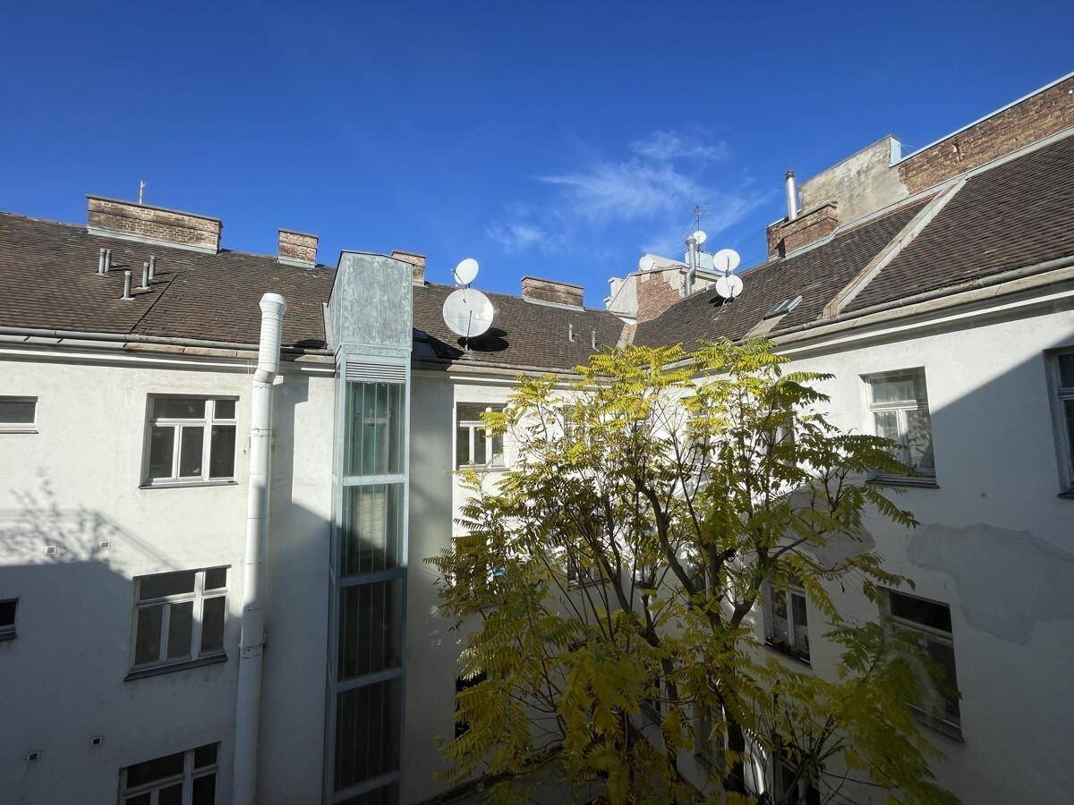Dachlandschaft eines Altbaus mit Satellitenschüsseln und Blick in den Innenhof.