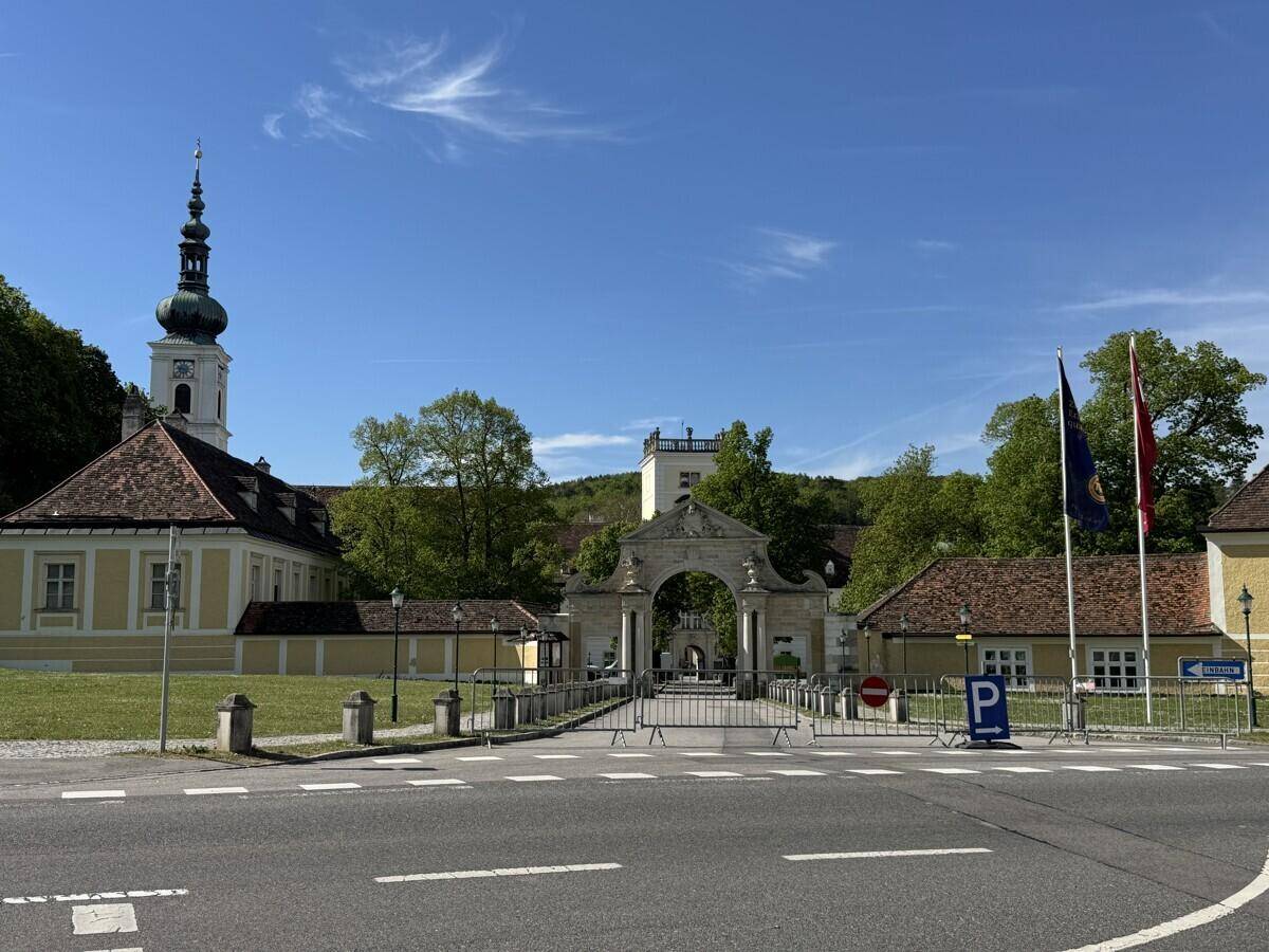 Historisches Gebäudeensemble mit markantem Kirchturm und einem großen Torbogen unter blauem Himmel.