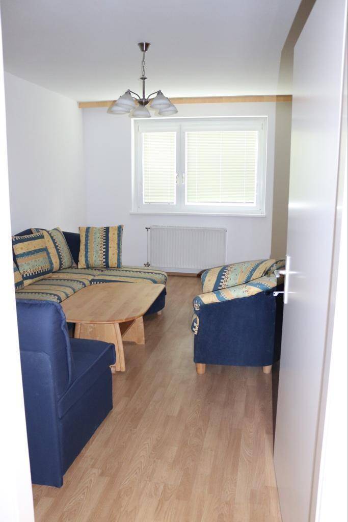 Wohnzimmer mit bequemen blauen Sofas, Couchtisch und Holzboden, ideal zum Entspannen.