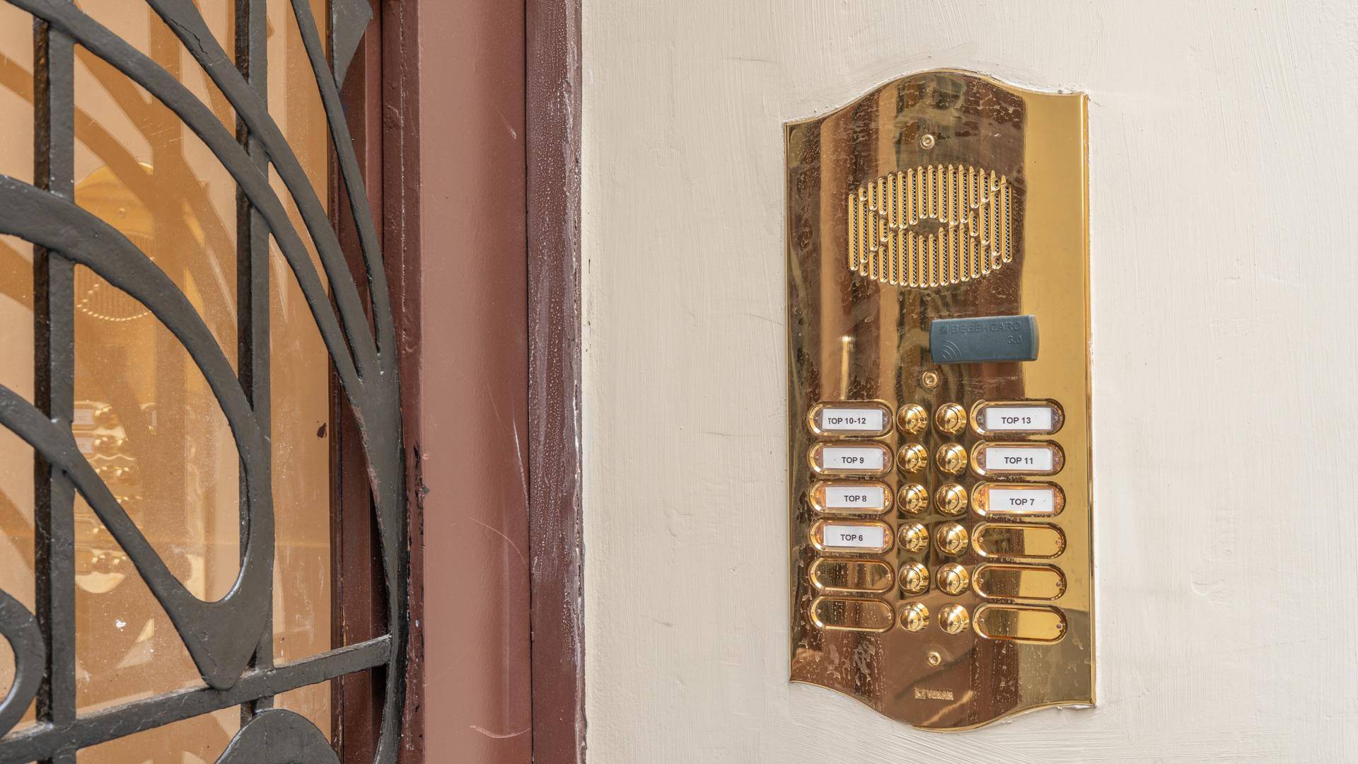 Goldene Gegensprechanlage mit vielen Klingelknöpfen am Eingangsbereich des Gebäudes.