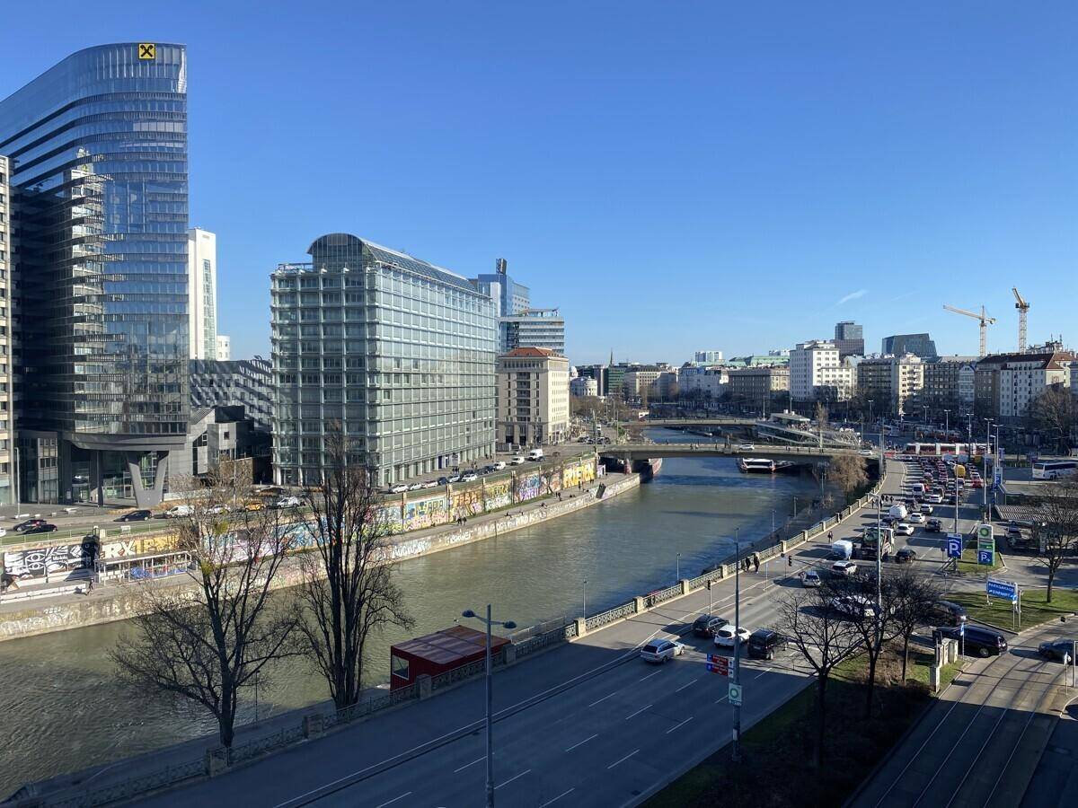 Weitläufiger Blick auf die Stadt mit Fluss, modernen Gebäuden und belebter Straße.