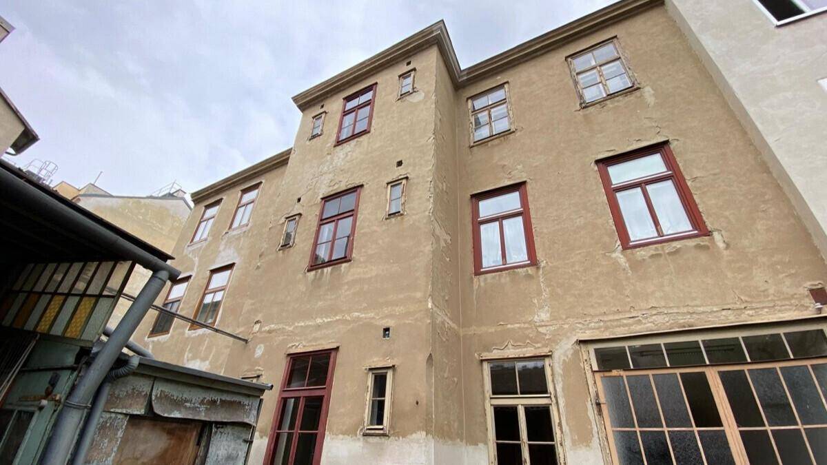 Rückfassade eines Altbaus mit vielen Fenstern und sichtbaren Gebrauchsspuren an der beigen Wand.