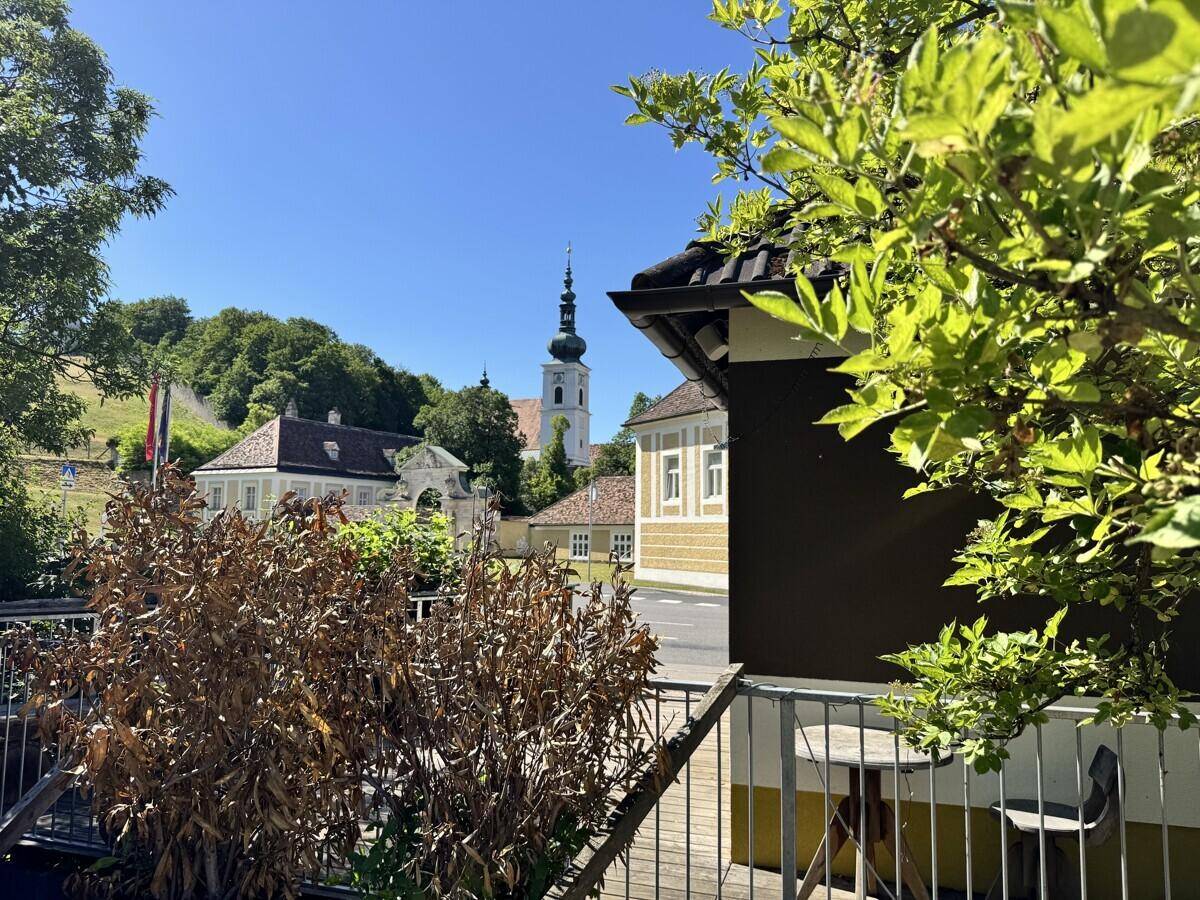 Terrasse mit üppigem Grün im Vordergrund und einem malerischen Blick auf die Umgebung.