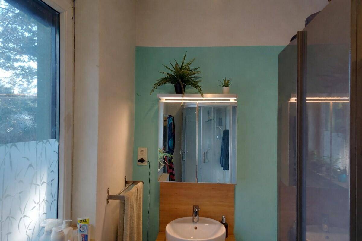 Badezimmer mit Fenster, Duschkabine und modernem Waschtisch mit Spiegelschrank.