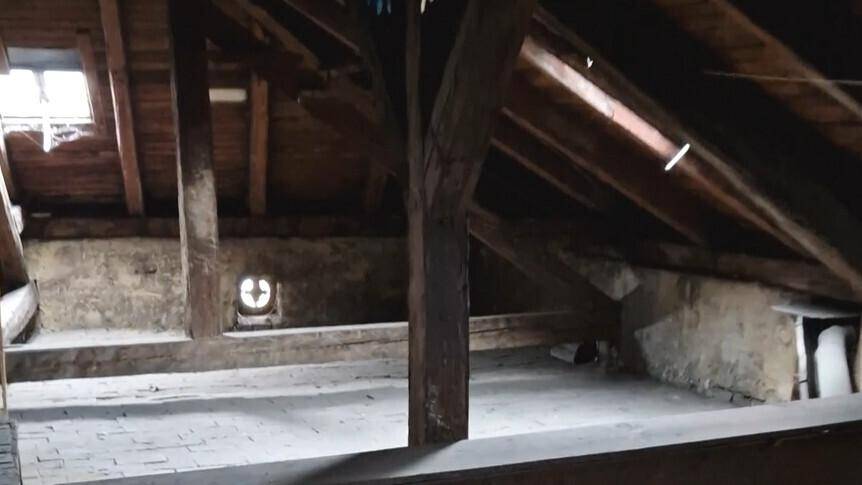 Geräumiger Dachboden mit freiliegenden Holzbalken und einem kleinen Dachfenster.