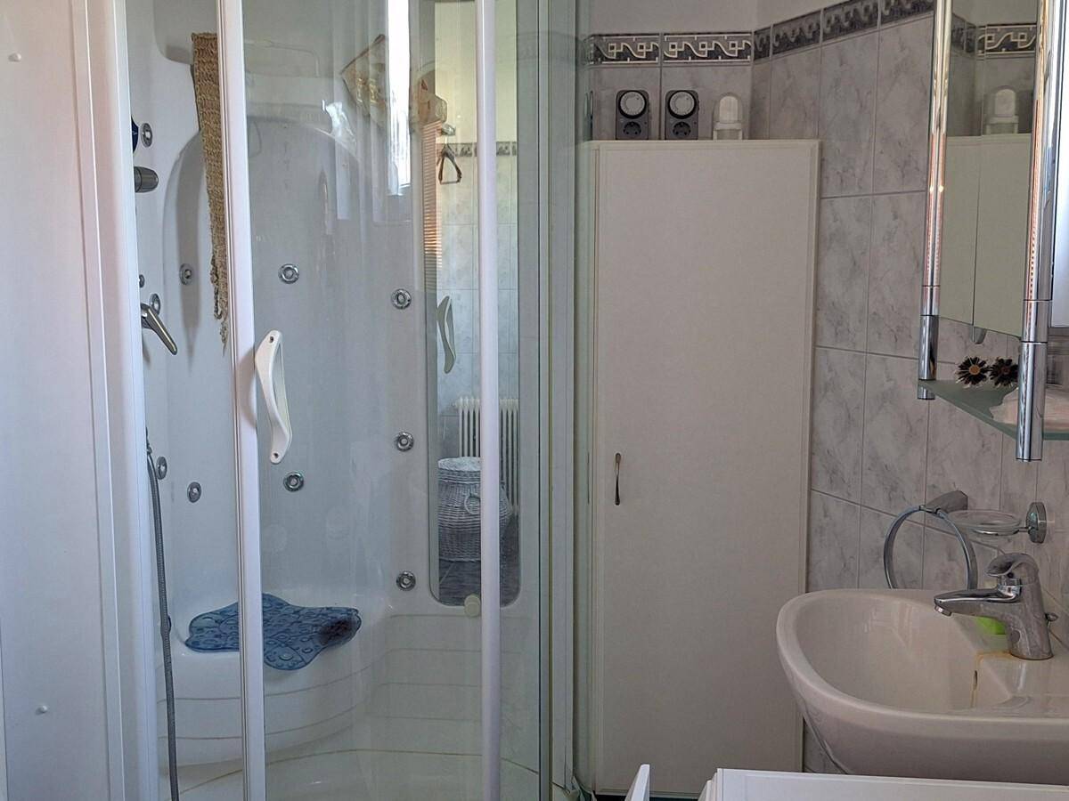 Funktionales Badezimmer mit Duschkabine, Einzelwaschbecken und hellen Fliesen, gut gepflegt und sauber.