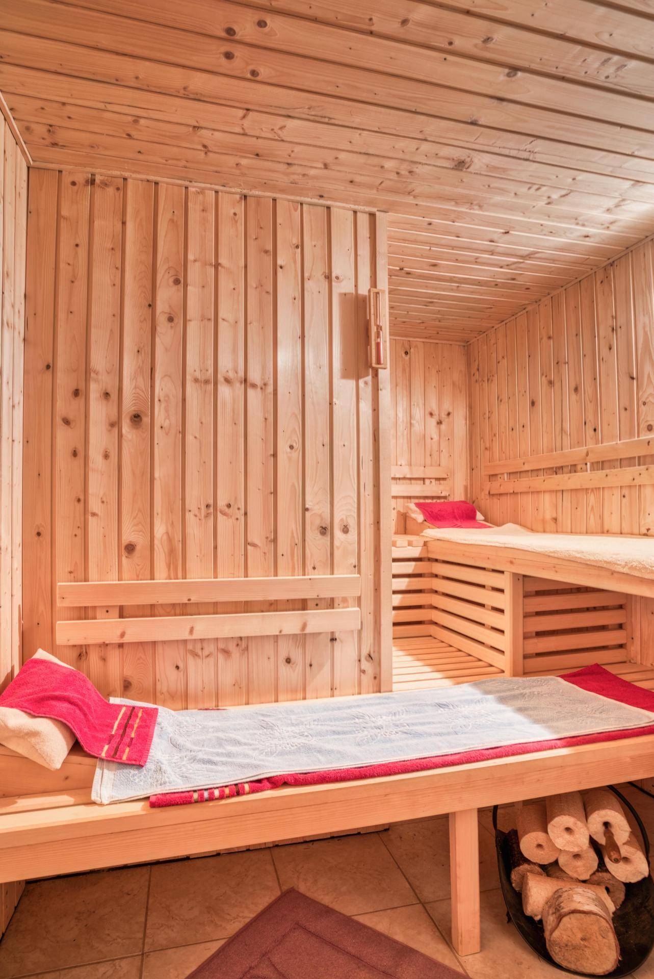 Helle Holzsauna mit mehreren Liegeflächen und traditionellem Ofen für entspannende Momente.