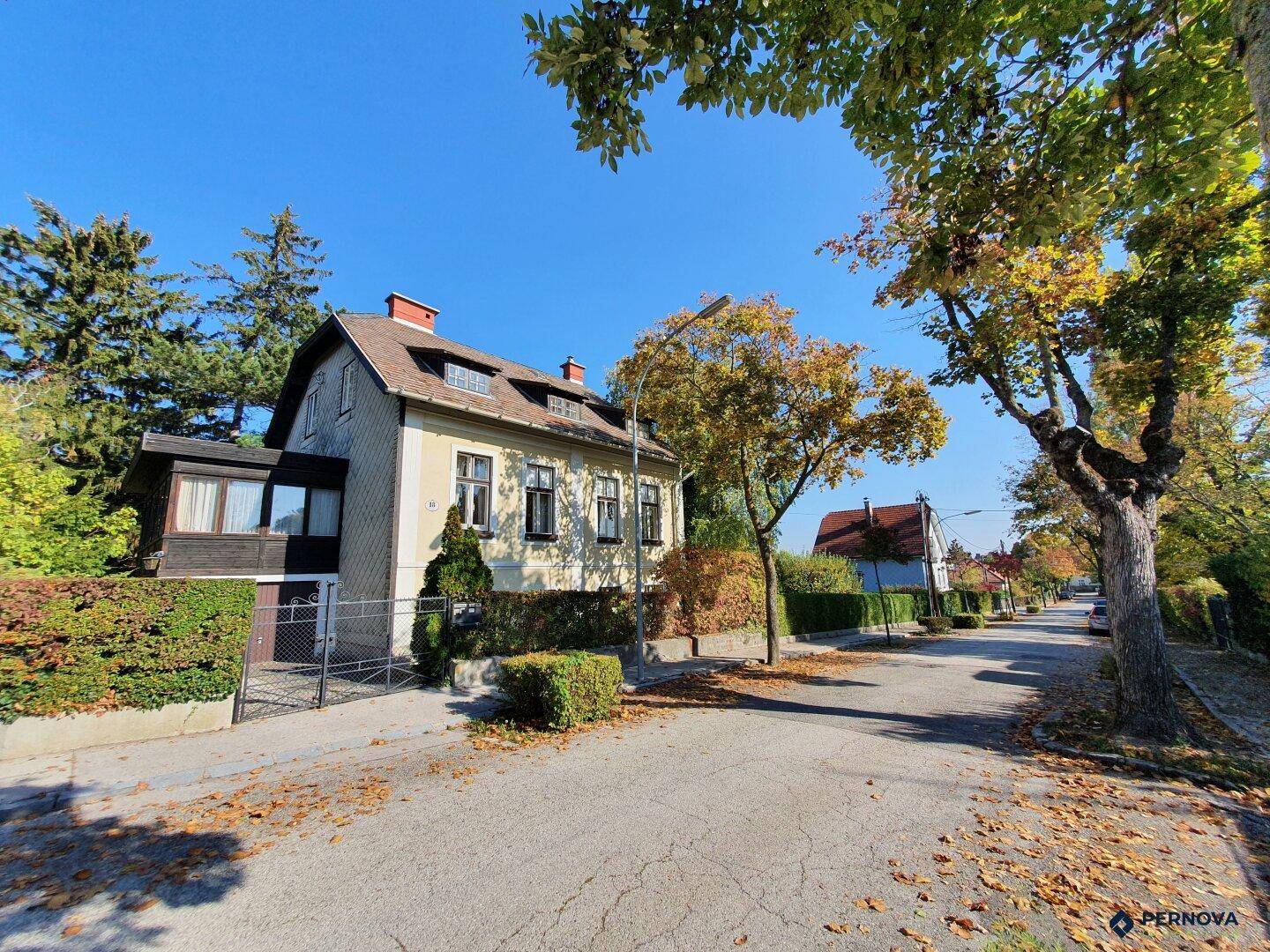 Das charmante Einfamilienhaus liegt an einer ruhigen Straße, umgeben von viel Grün und Bäumen.