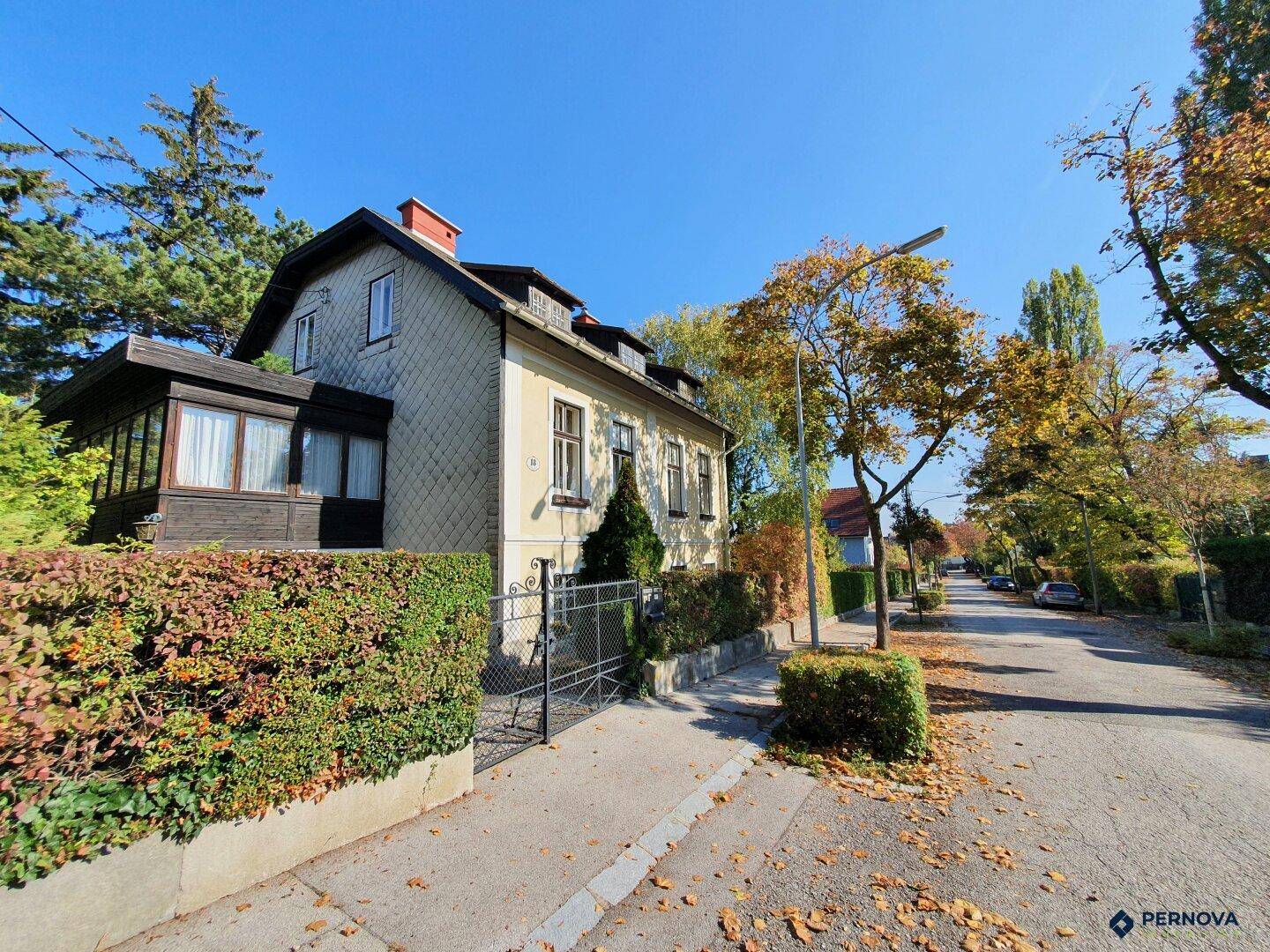 Das Haus von der Straße aus gesehen, umgeben von Bäumen und einem gepflegten Vorgarten.
