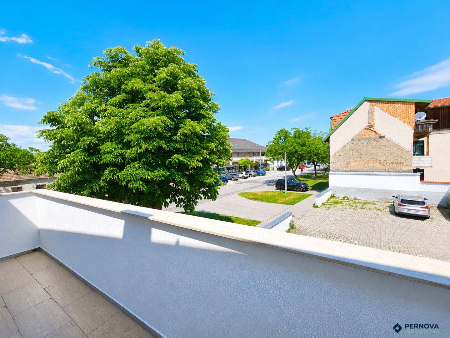 Weitläufiger Blick vom Balkon auf die umliegende Wohngegend und viel Grün.