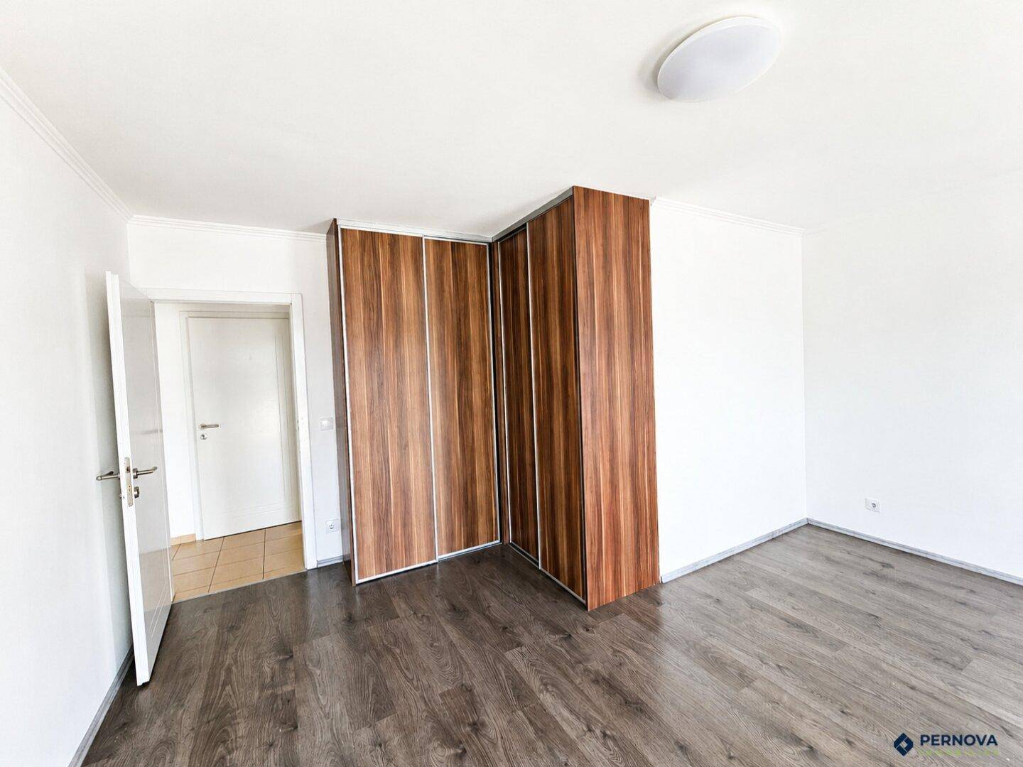 Schlafzimmer mit integrierten Holzschränken und dunklem Laminatboden.