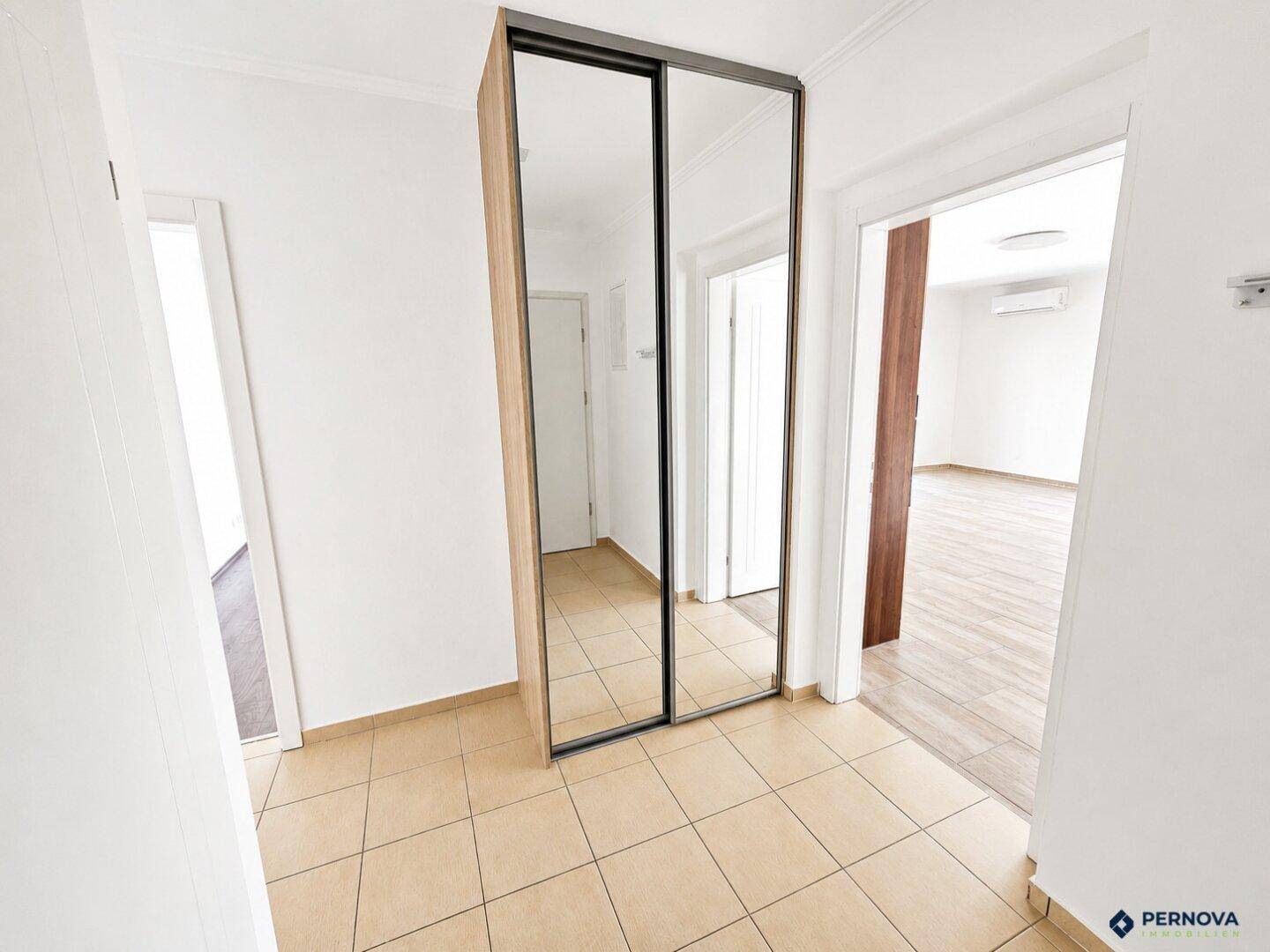Heller Flur mit Fliesenboden und einem großen Spiegelschrank, der zu weiteren Räumen führt.
