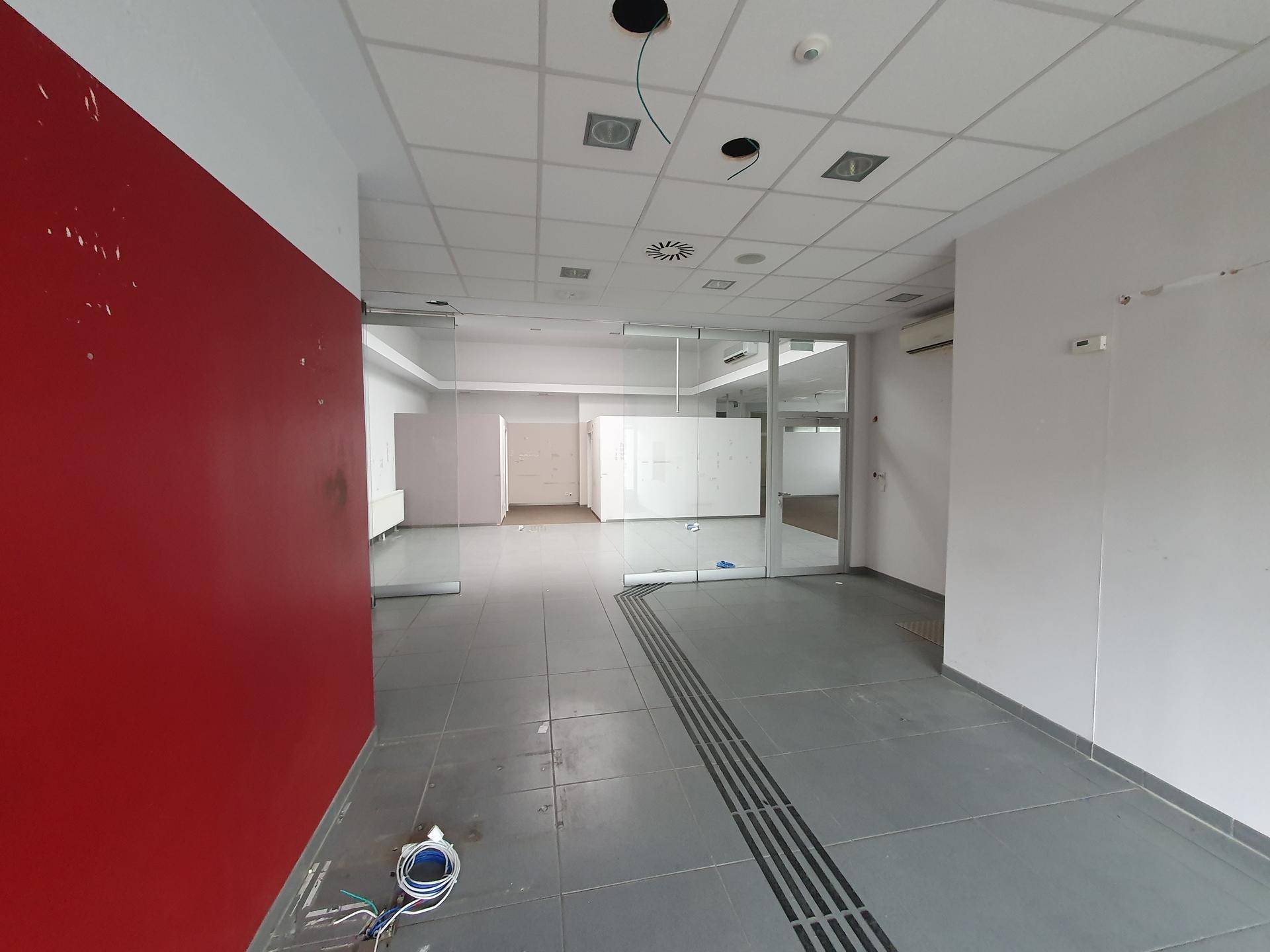 Moderner Bürobereich mit roter Akzentwand und Glasabtrennungen, ideal für kreative Arbeitsumgebungen.